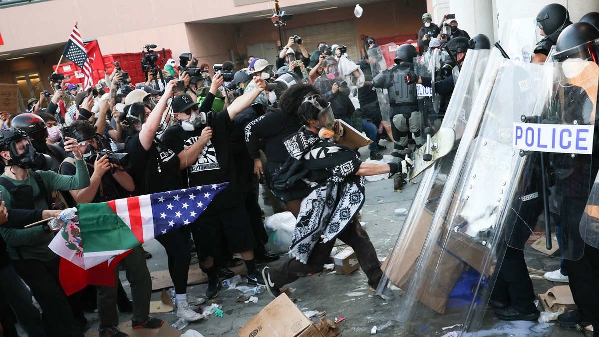 A protestor attacks a police officer with a skateboard during a protest in Los Angeles