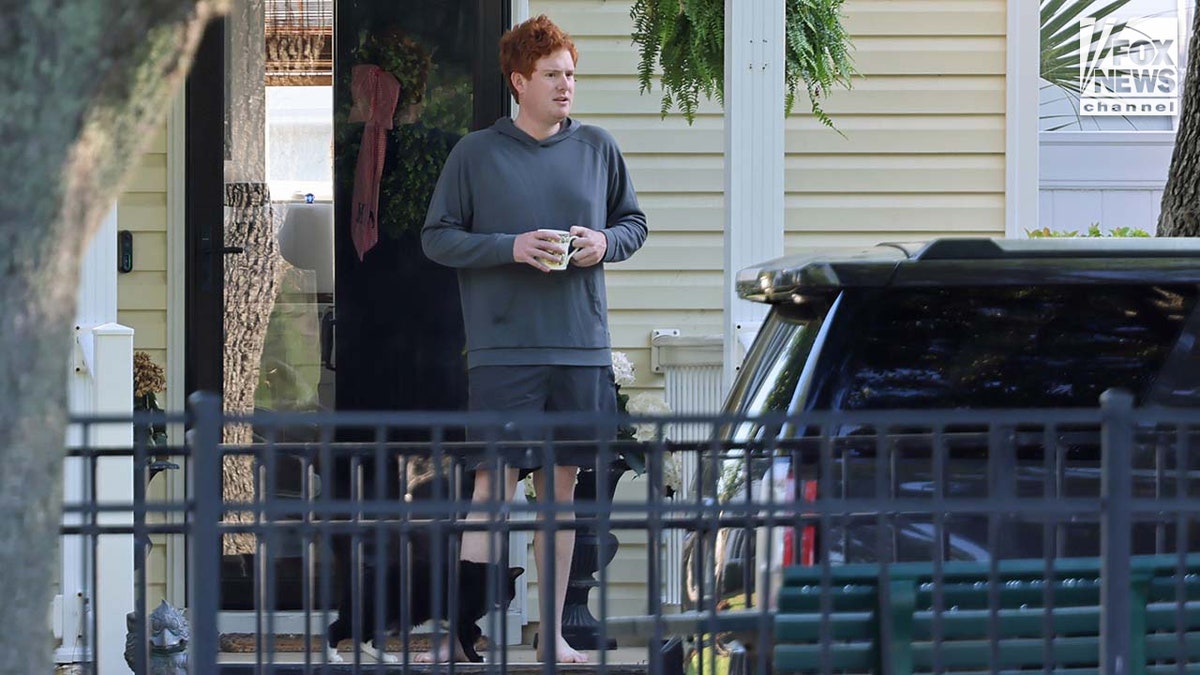 Buster Murdaugh sitting on the front porch holding a coffee cup.