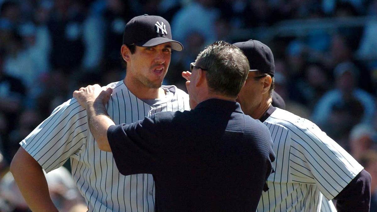 Yankees trainer Gene Monahan checking pitcher Carl Pavano after head injury