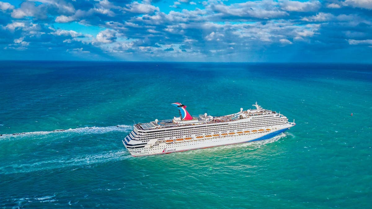 A Carnival Cruise ship sails in a blue ocean.