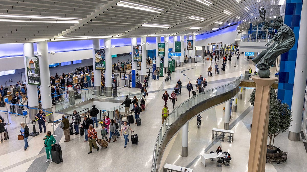 Security lines at Charlotte-Douglas International Airport departures level with travelers waiting.
