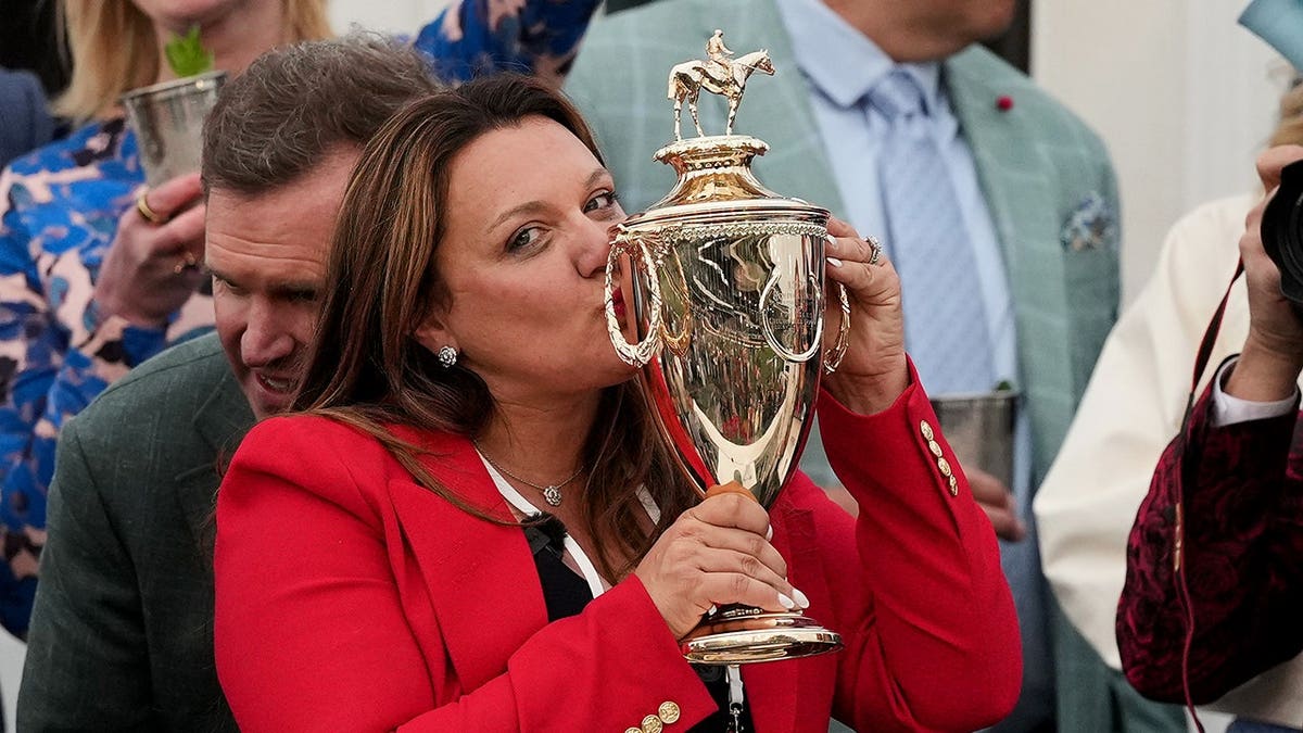 Trainer Cherie DeVaux kissing trophy at Churchill Downs