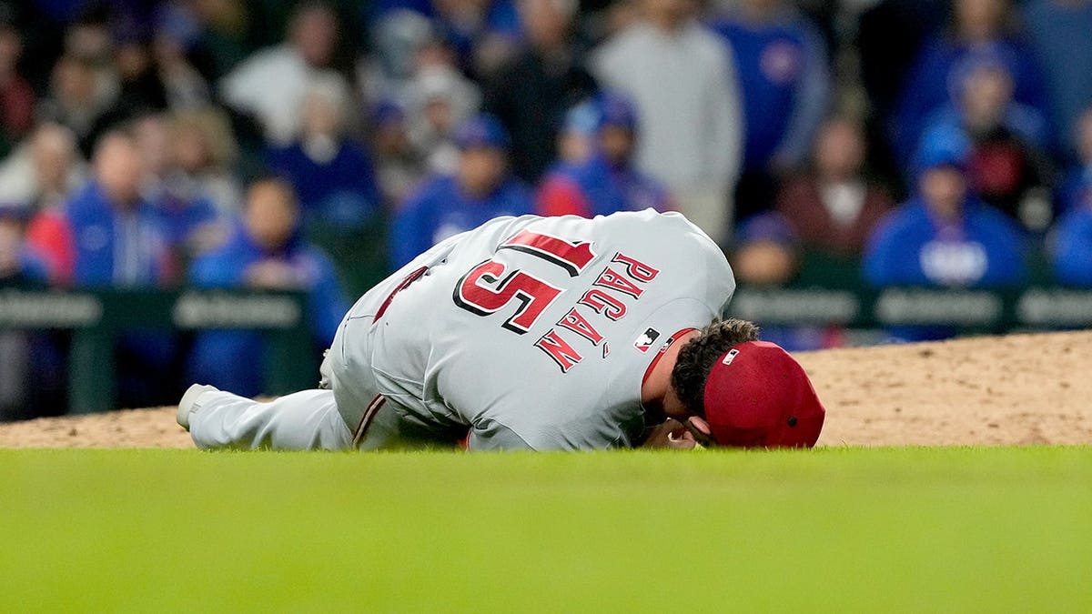 Cincinnati Reds relief pitcher Emilio Pagán lying on the field during a baseball game.