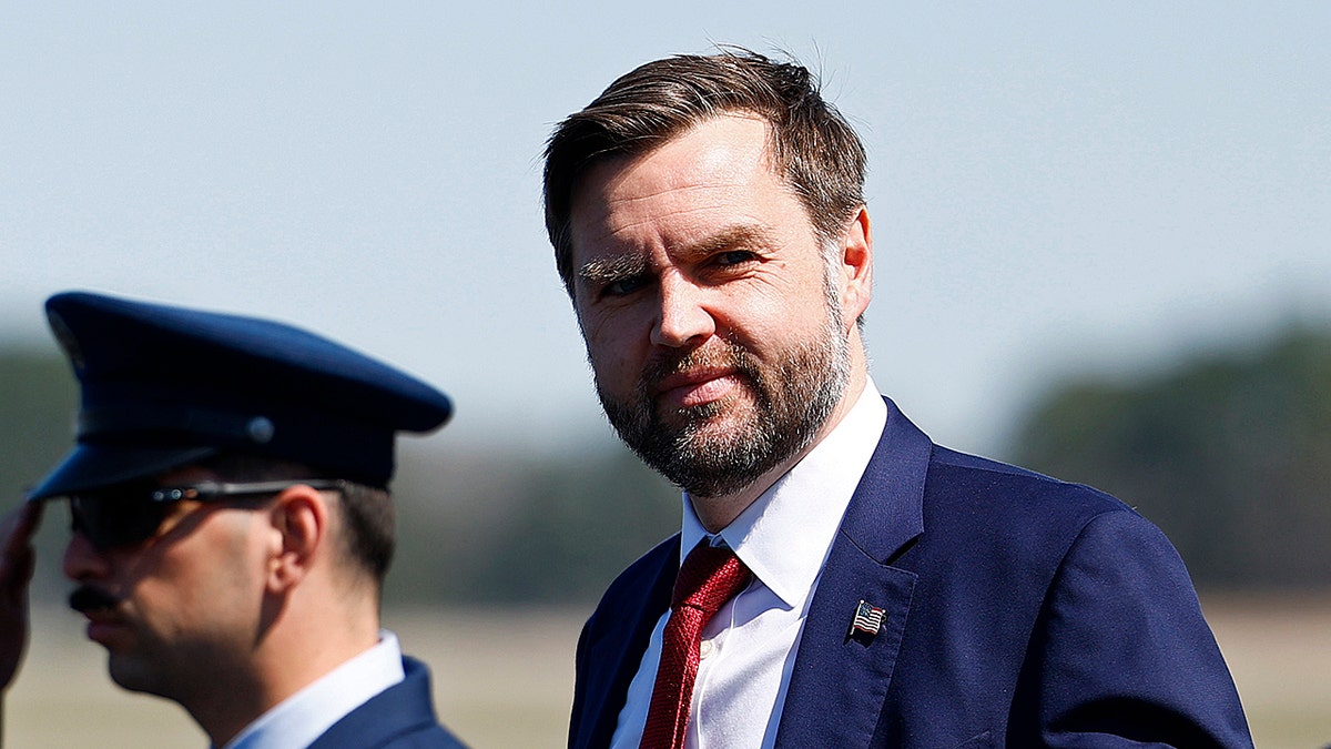 Vice President JD Vance standing next to a saluting soldier
