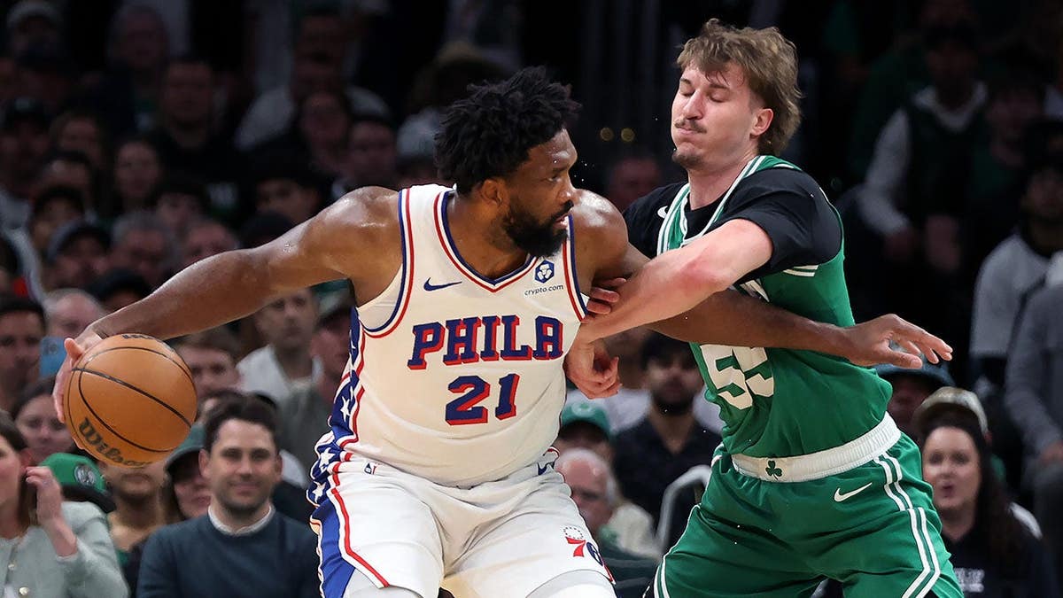 Boston Celtics' Jayson Baylor Scheierman defending Philadelphia 76ers' Joel Embiid during basketball game