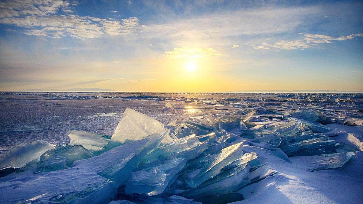 A frozen Lake Baikal covered in snow and ice under a clear sky