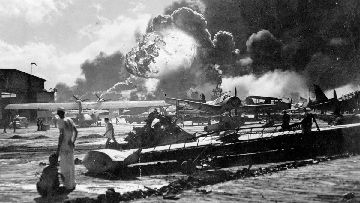 Sailors standing amid wreckage watching USS Shaw explode at Naval Air Station Ford Island Pearl Harbor