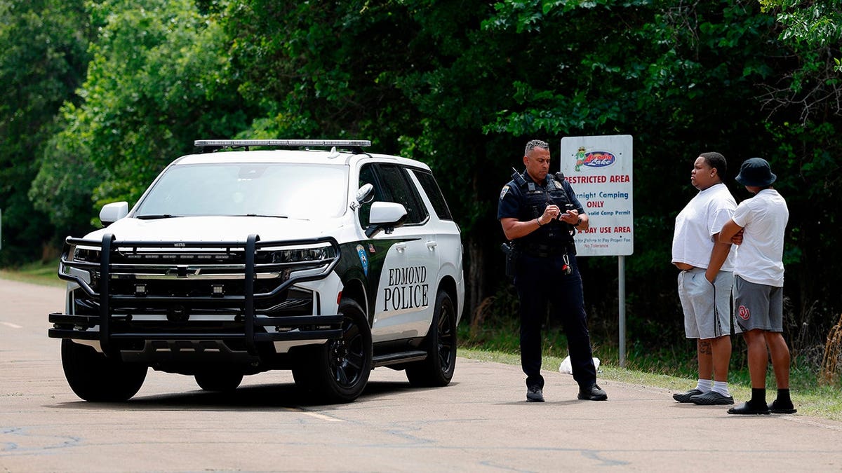 Police talking to two men at the entrance of Scissortail Campground at Arcadia Lake in Edmond, Okla.