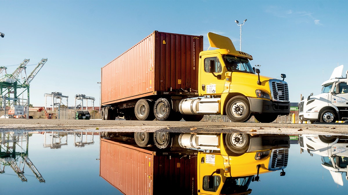 A truck driving past a body of water at a Port of Oakland shipping terminal