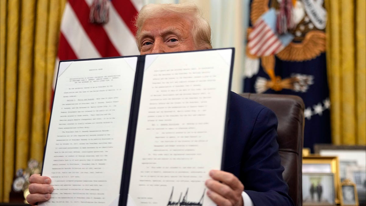 President Donald Trump holding an executive order in the Oval Office