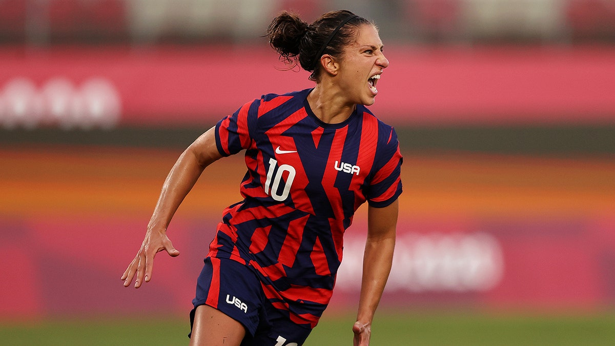 Carli Lloyd celebrating after scoring a goal during a women's soccer match.