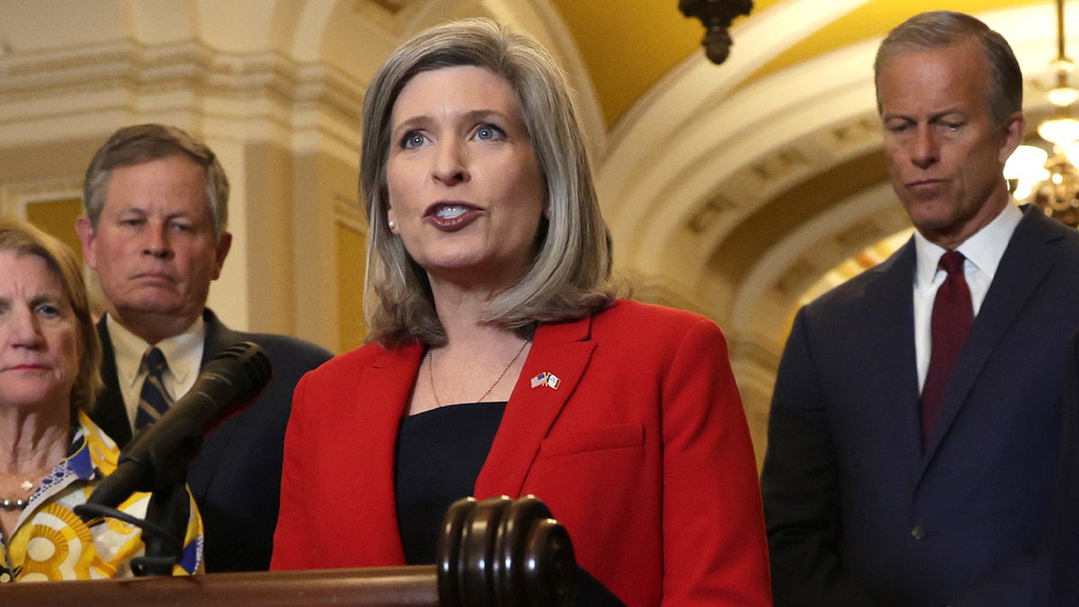 Sen. Joni Ernst speaking during a news briefing at the U.S. Capitol with other senators listening