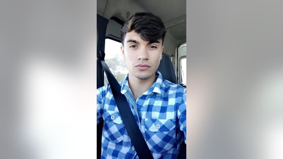 Emilio Valdez wearing a blue checkered shirt and a seatbelt taking a selfie.