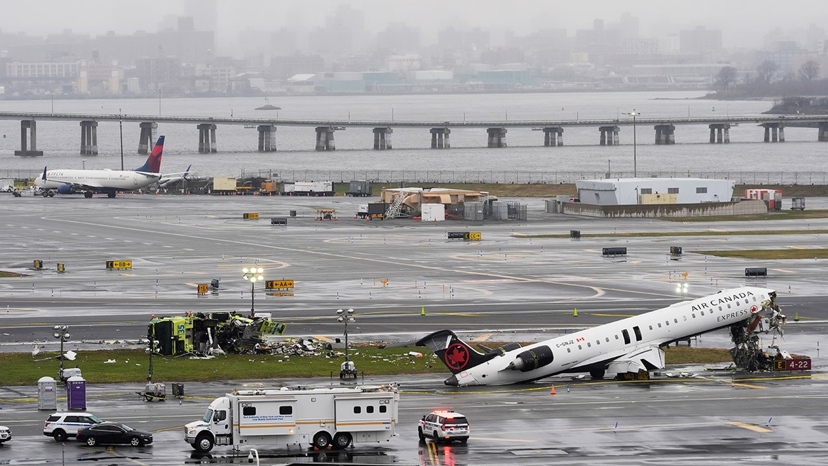 An Air Canada jet and Port Authority fire truck parked on the runway at LaGuardia Airport