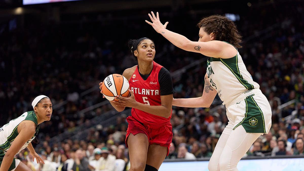 Angel Reese controlling the ball while defended by Stefanie Dolson at Climate Pledge Arena