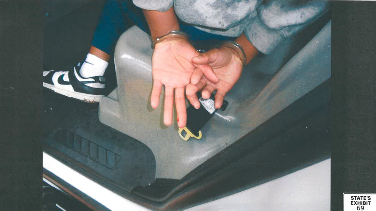 Handcuffed person in backseat of cop car.