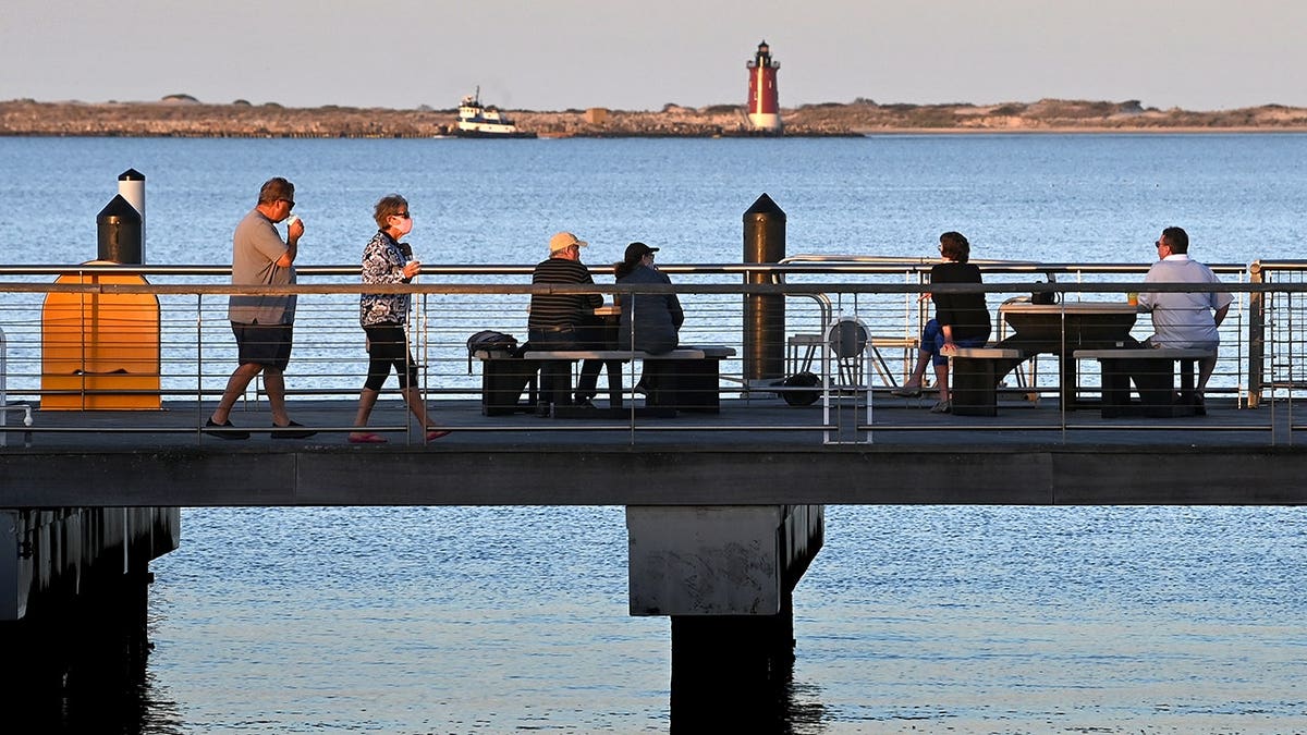 Diners eating on a pier next to Grain On the Rocks restaurant at Cape May-Lewes Ferry Terminal in Lewes Delaware