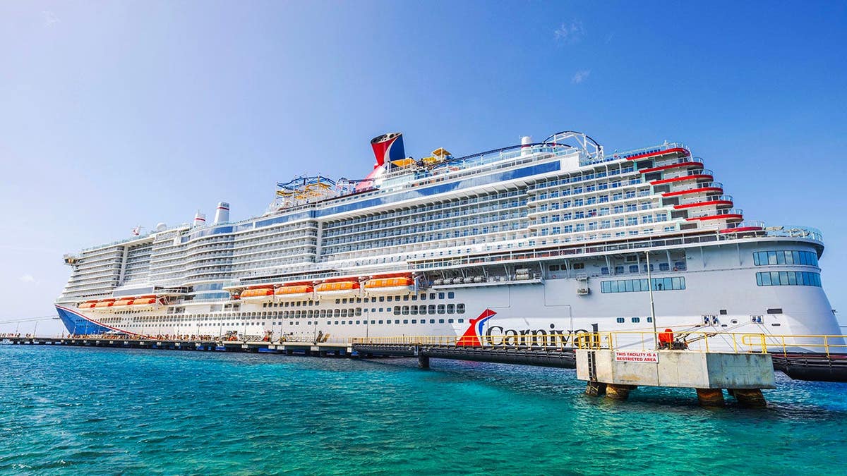 Carnival cruise ship docked in turquoise Caribbean Sea water near pier in Willemstad Curacao