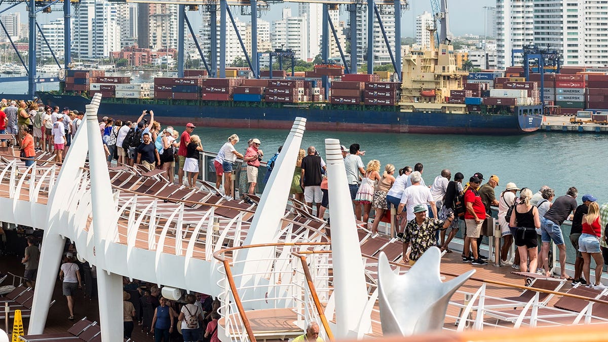 Passengers aboard a cruise ship admiring Cartagena cityscape with container port in foreground
