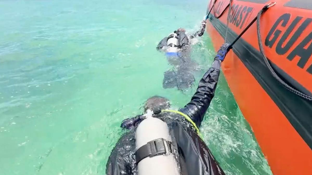 photo shows divers next to coast guard boat