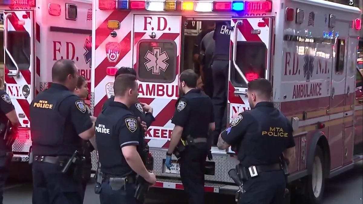 MTA police officers stand near an ambulance outside Penn Station after a stabbing incident that injured multiple people.