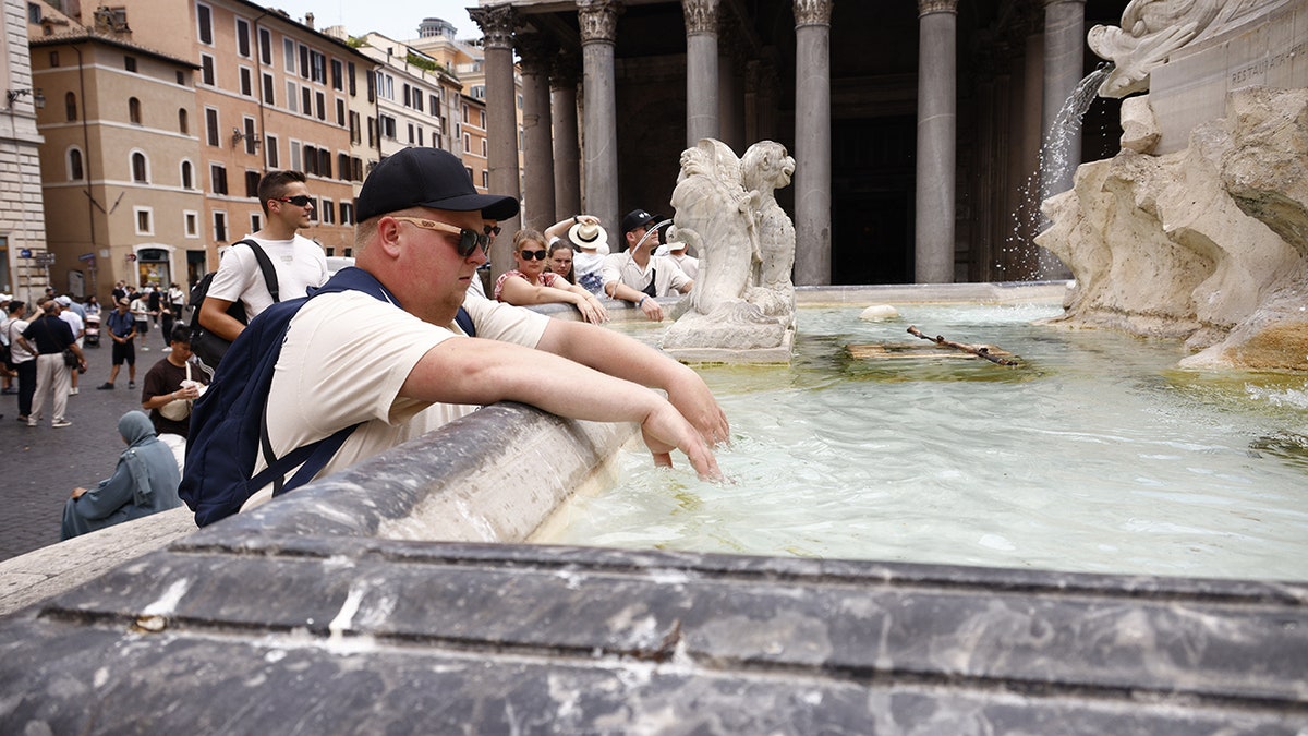 Tourist in Rome dips hands in fountain