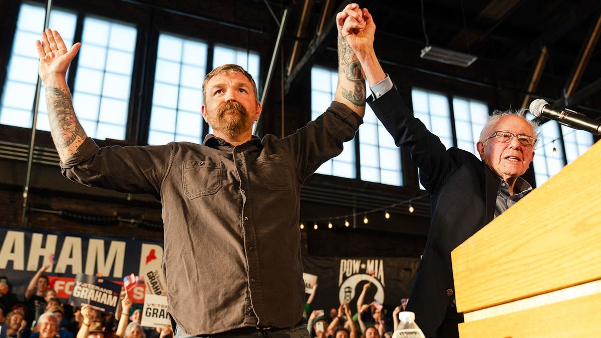 Graham Platner and Senator Bernie Sanders standing together at a Fighting Oligarchy event in Portland, Maine