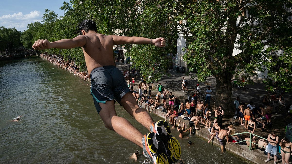 A swimmer diving into the Canal Saint-Martin in Paris from an unapproved spot