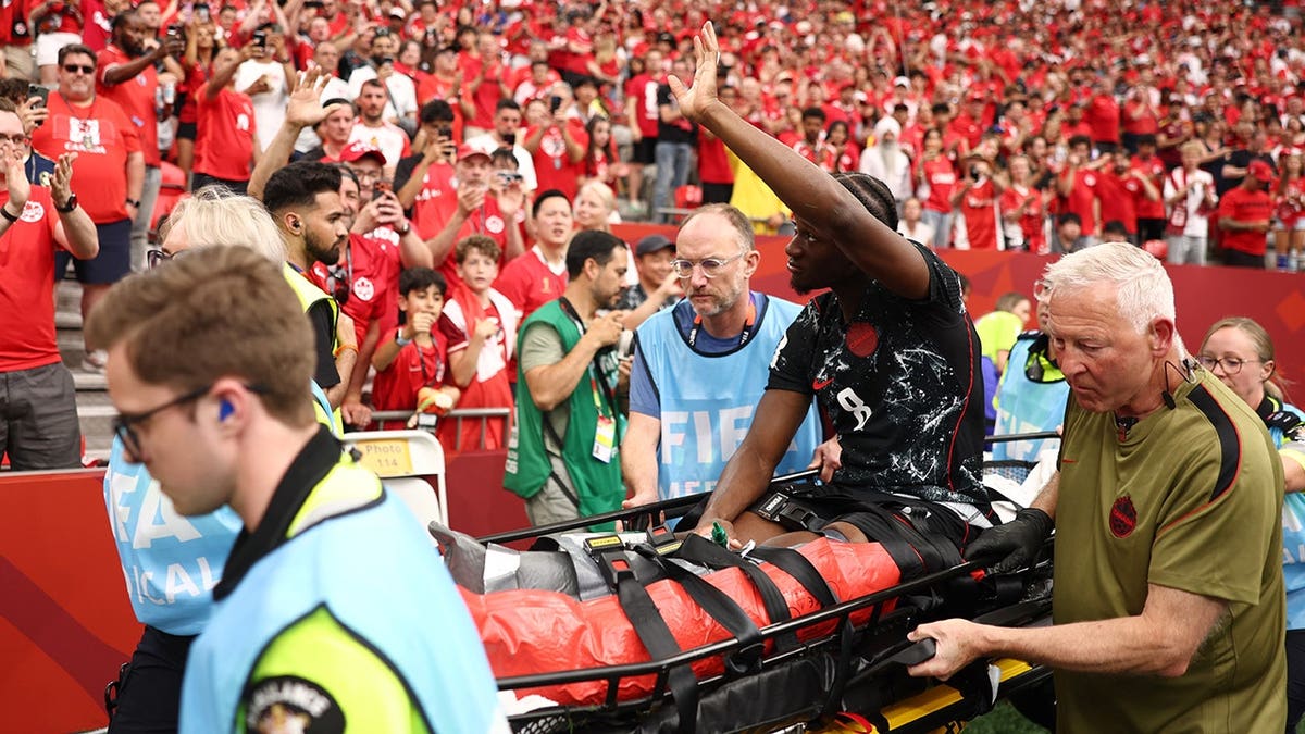 Ismael Kone of Canada waving to crowd while being stretched off soccer field