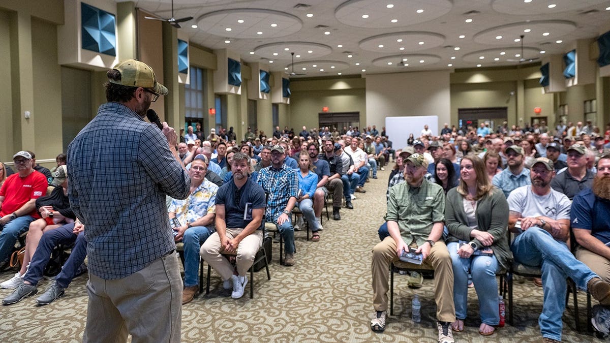 Jack Carr speaking to a crowd in a conference room.