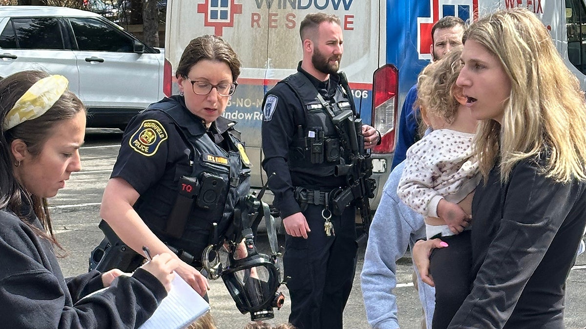 A woman gathering children outside Temple Israel synagogue as law enforcement respond