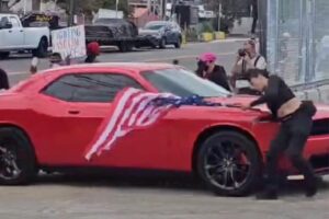 Anti-ICE protester hit by car while waving upside-down US flag outside Delaney Hall Anti-ICE protester hit by car while waving upside-down US flag outside Delaney Hall