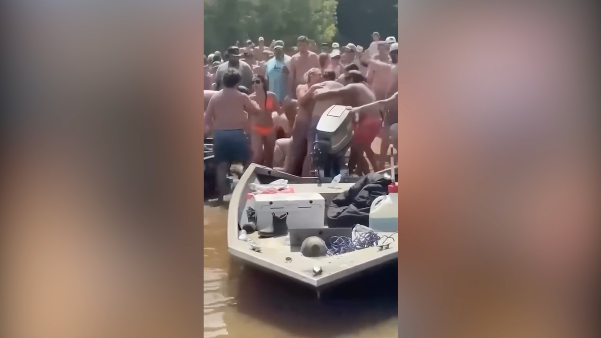 A large crowd surrounds a fight at the 601 Sand Bar on the Congaree River in South Carolina