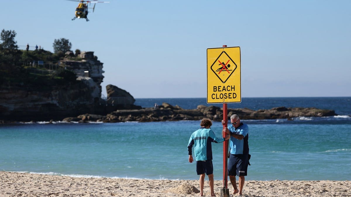 Lifeguards erect a sign that says 