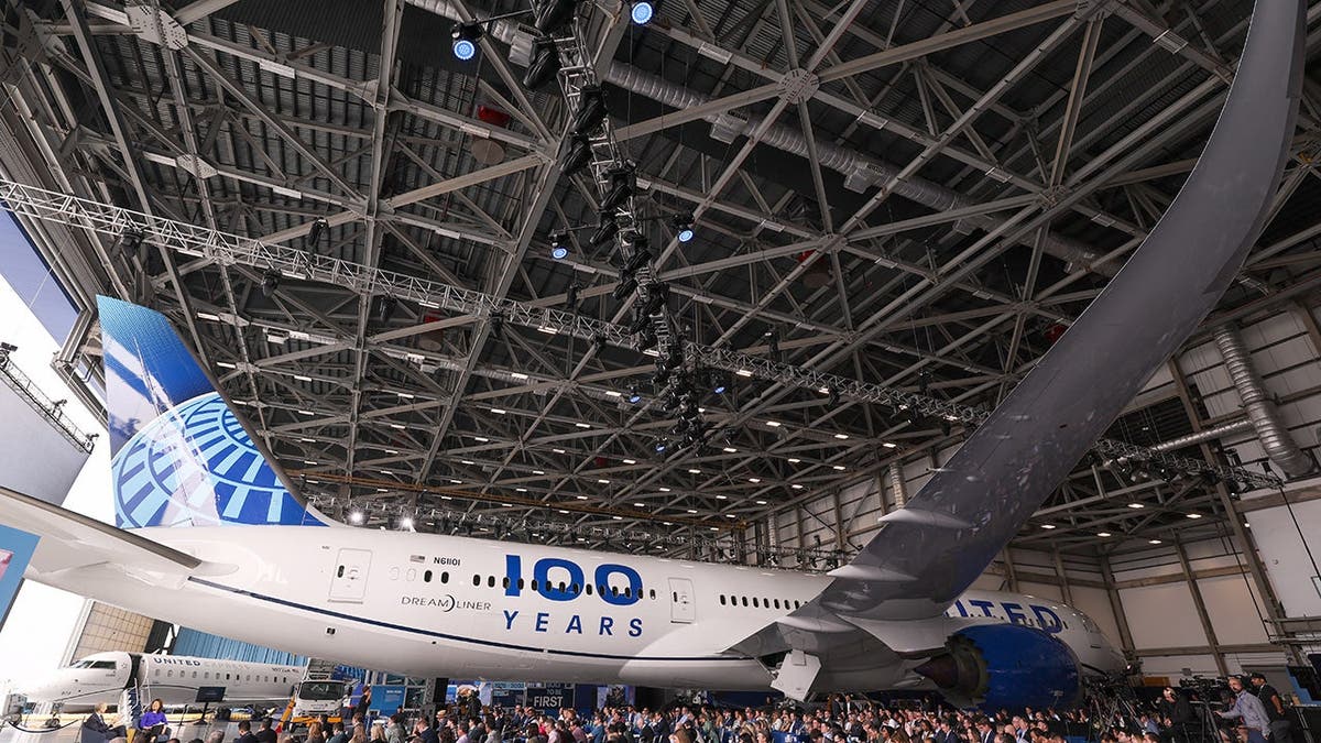 A United Airplane with people surround it in a hangar.