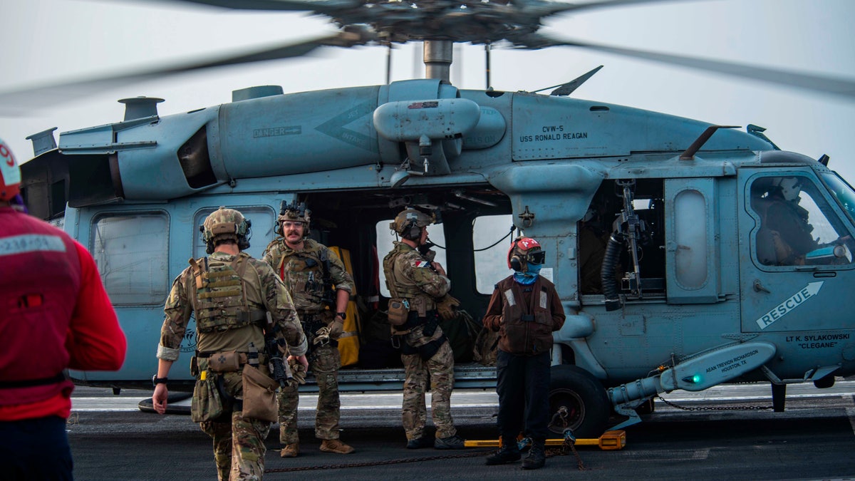 FILE - In this photo provided by the U.S. Navy, sailors assigned to an explosive ordnance unit board an MH-60S Seahawk helicopter on the flight deck of aircraft carrier USS Ronald Reagan to head to an oil tanker that was attacked off the coast of Oman in the Arabian Sea on Friday, July 30, 2021.