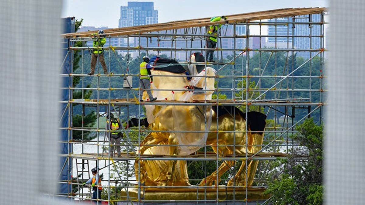 Workers remove scaffolding from Arts of War horse statue.