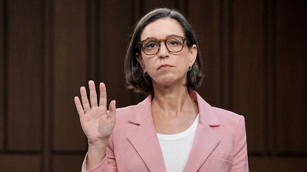 Liz Oyer standing with her right hand raised to take an oath during a Senate hearing.