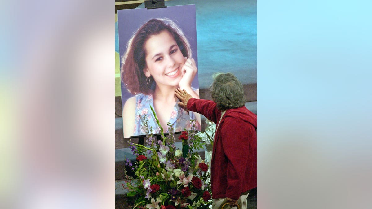 An unidentified mourner touches a picture of Laci Peterson at a memorial service.