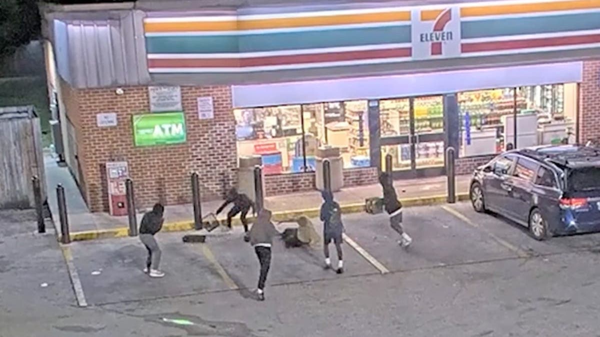 Six hooded suspects hover an elderly man on a sidewalk outside gas station