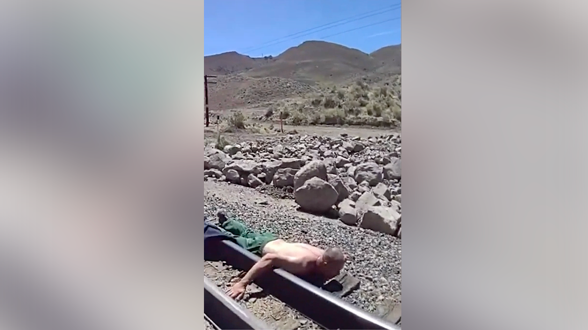 Escaped inmate Chase Orput lies shirtless on railroad tracks before deputies take him into custody.