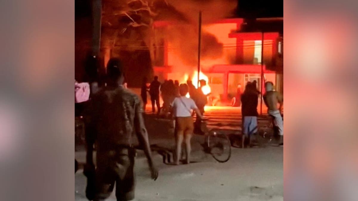 Protesters stand near a fire outside a Communist Party headquarters in Morón, Cuba during overnight unrest.