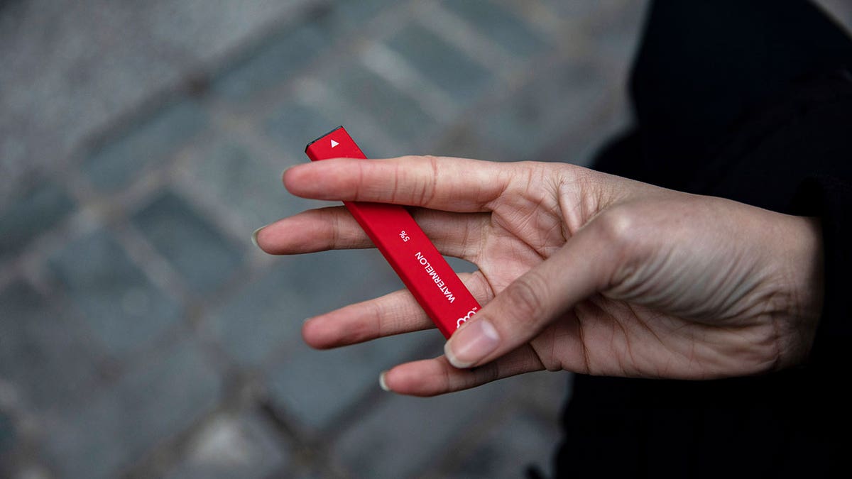 In this Jan. 31, 2020 photo a woman holds a Puff Bar flavored disposable vape device in New York.