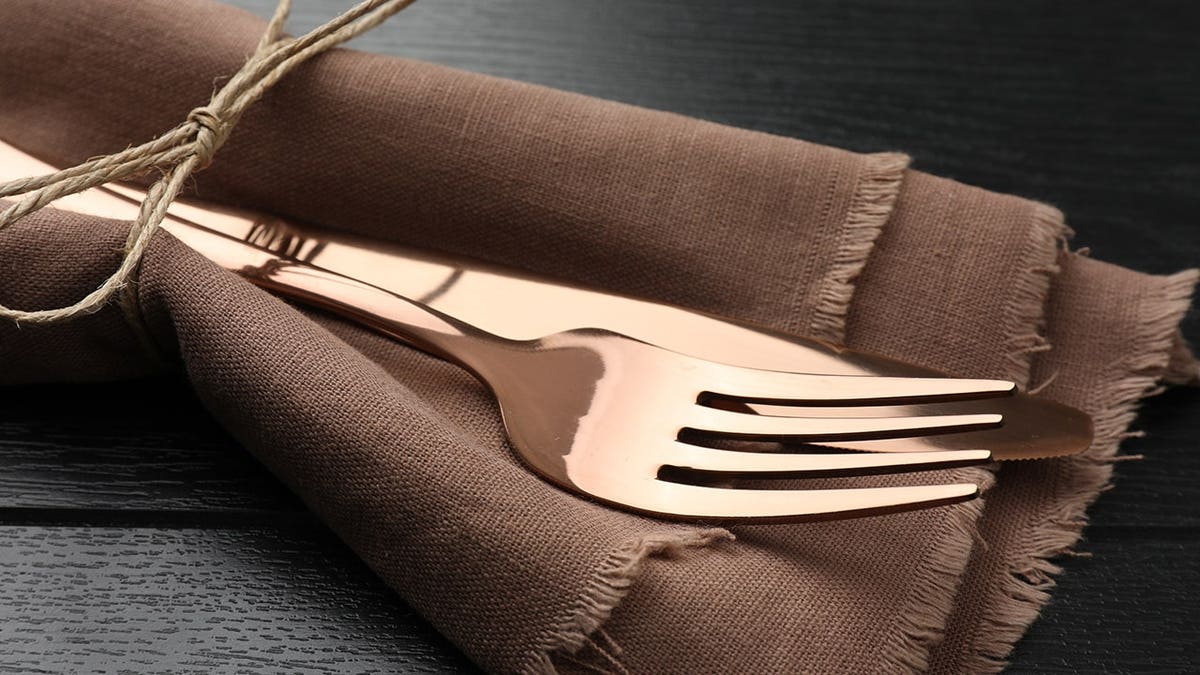 Cutlery and napkin arranged on a black wooden table