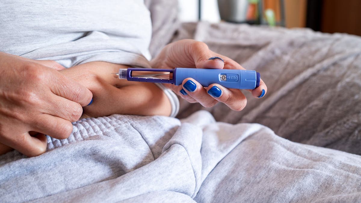 A person injects herself with a weight-loss drug.