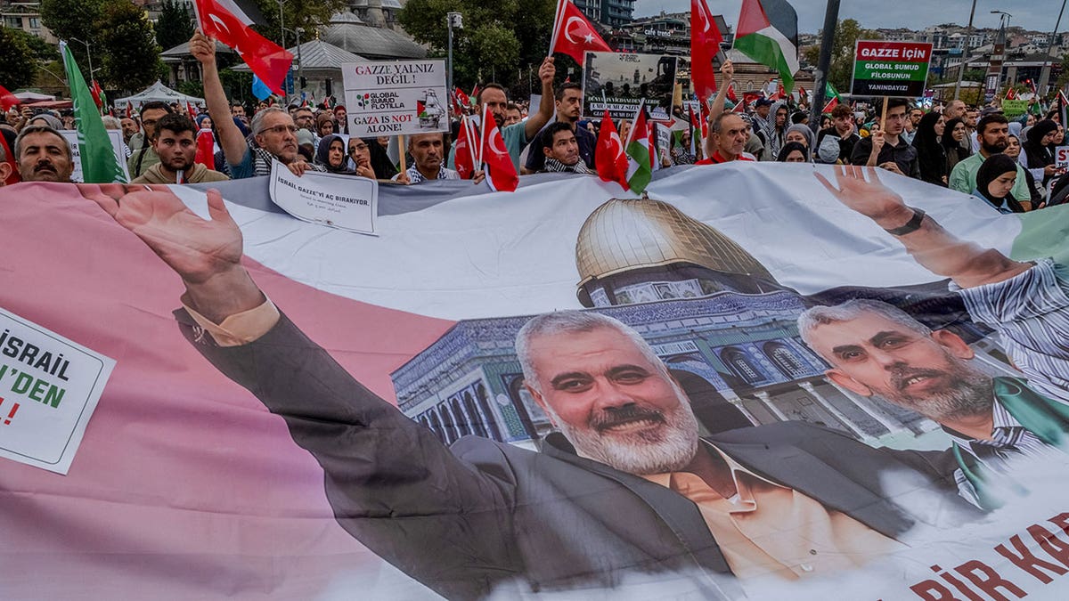 A group of protesters seen carrying a banner with pictures of the slain Hamas leaders Ismail Haniyeh and Yahya Sinwar.