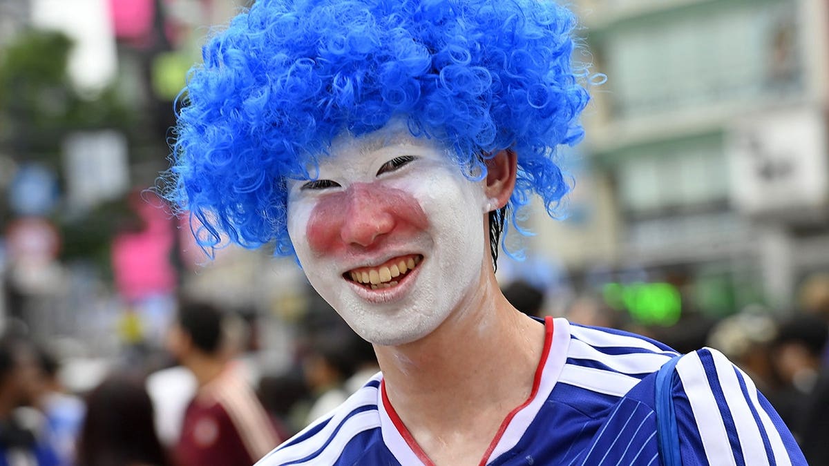 Man dressed in a blue Japan soccer uniform, a blue wig and face paint.