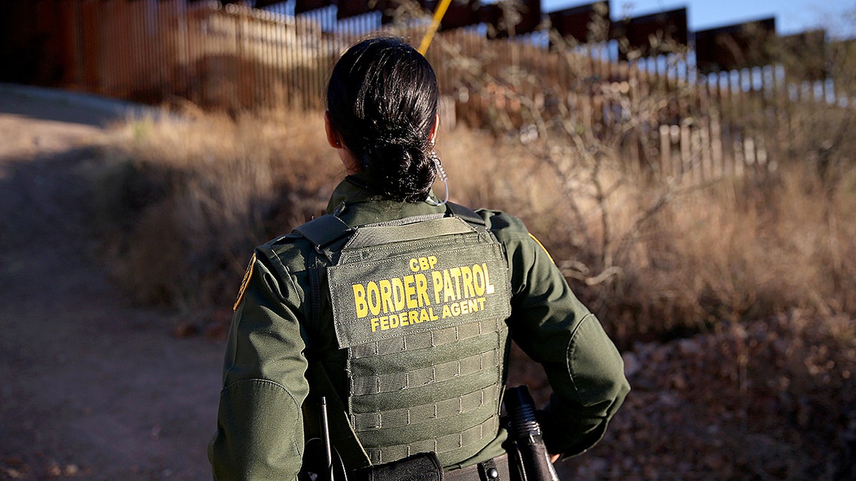 Nicole Ballistrea stands near the U.S.-Mexico border fence while looking out across the landscape.