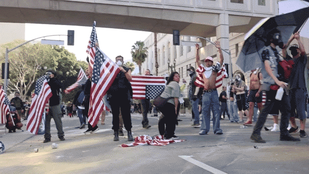Several protesters wave American flags in a city street