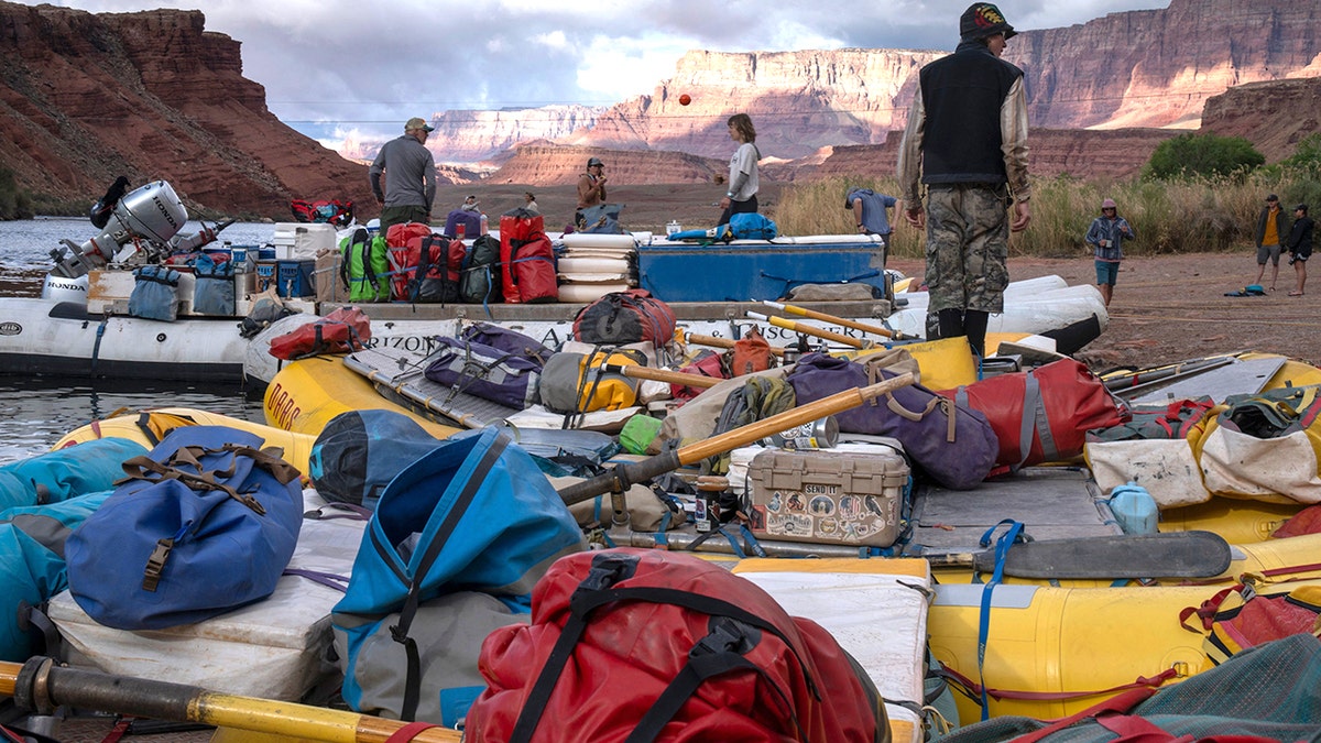 rafters prepare equipment near canyon river bank